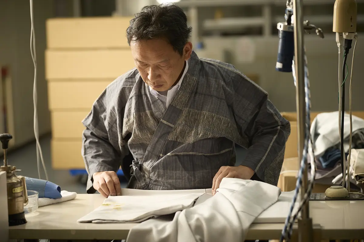 職人が着物のしみや色を確認する様子