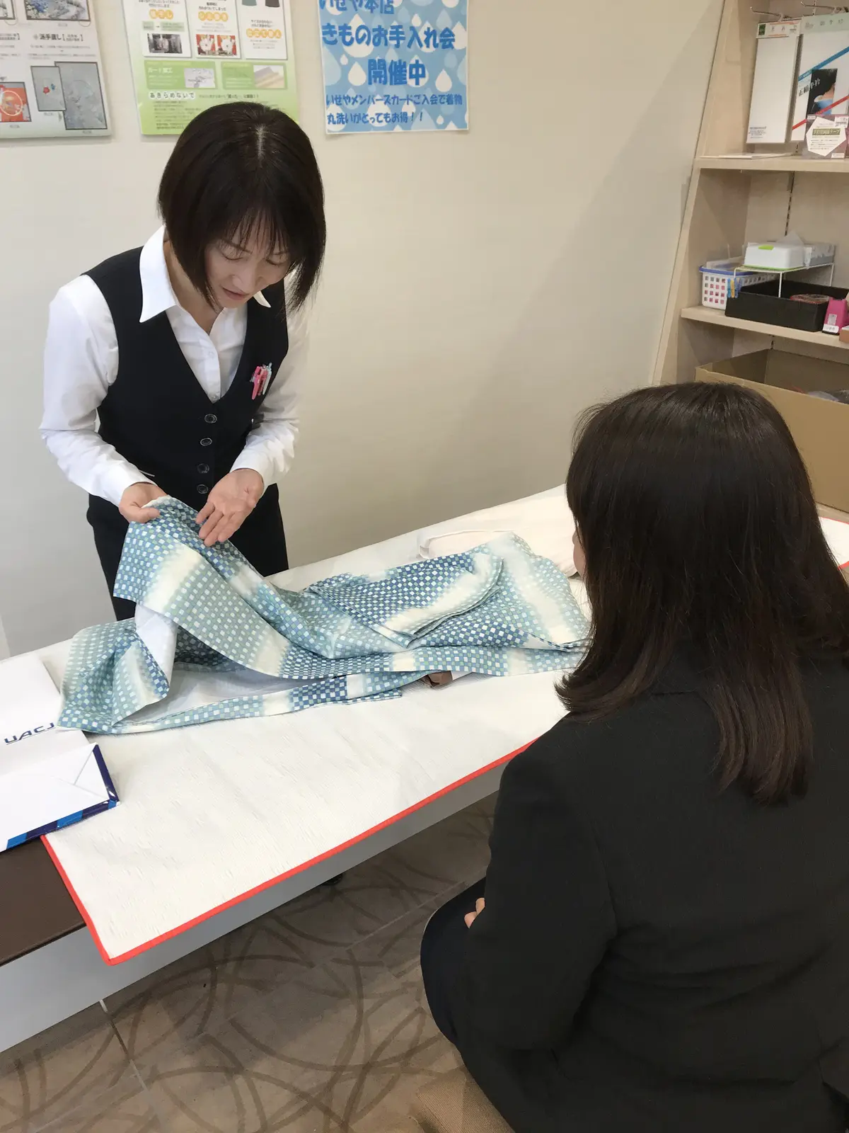 いせや本店でスタッフがお客様と着物の状態を確認する様子