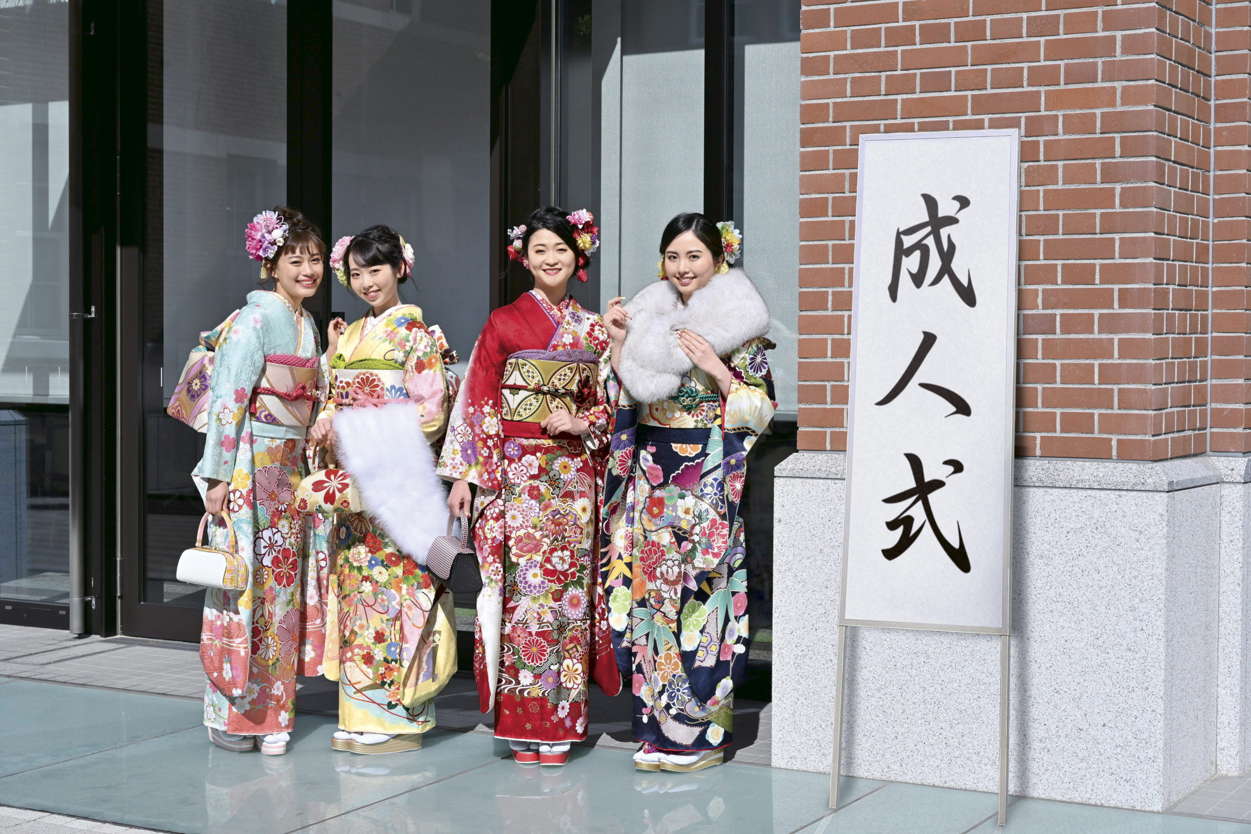 写真：成人式会場の前で写真を撮る振袖の女性4人組