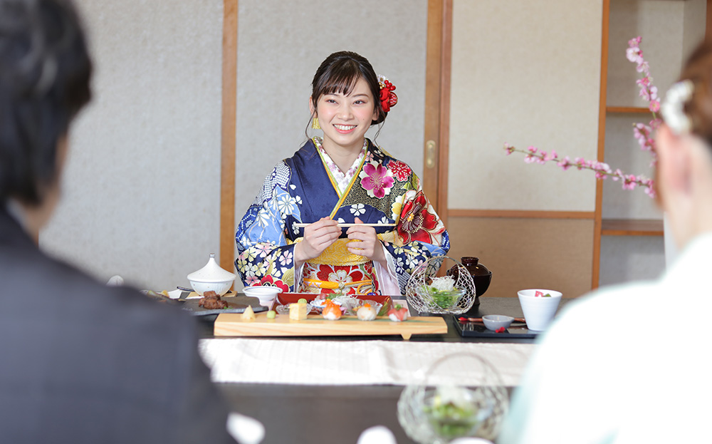 写真：和食を食べようとする青色の振袖を着た女性