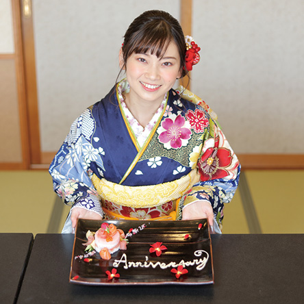 写真：お祝いのケーキを持つ振袖を着た女性