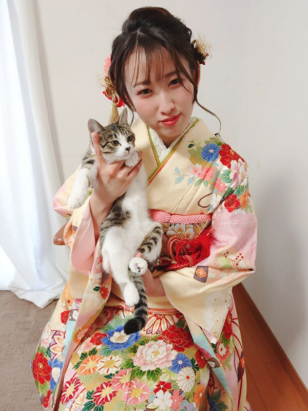 クリーム色の振袖を着た猫を抱く女性